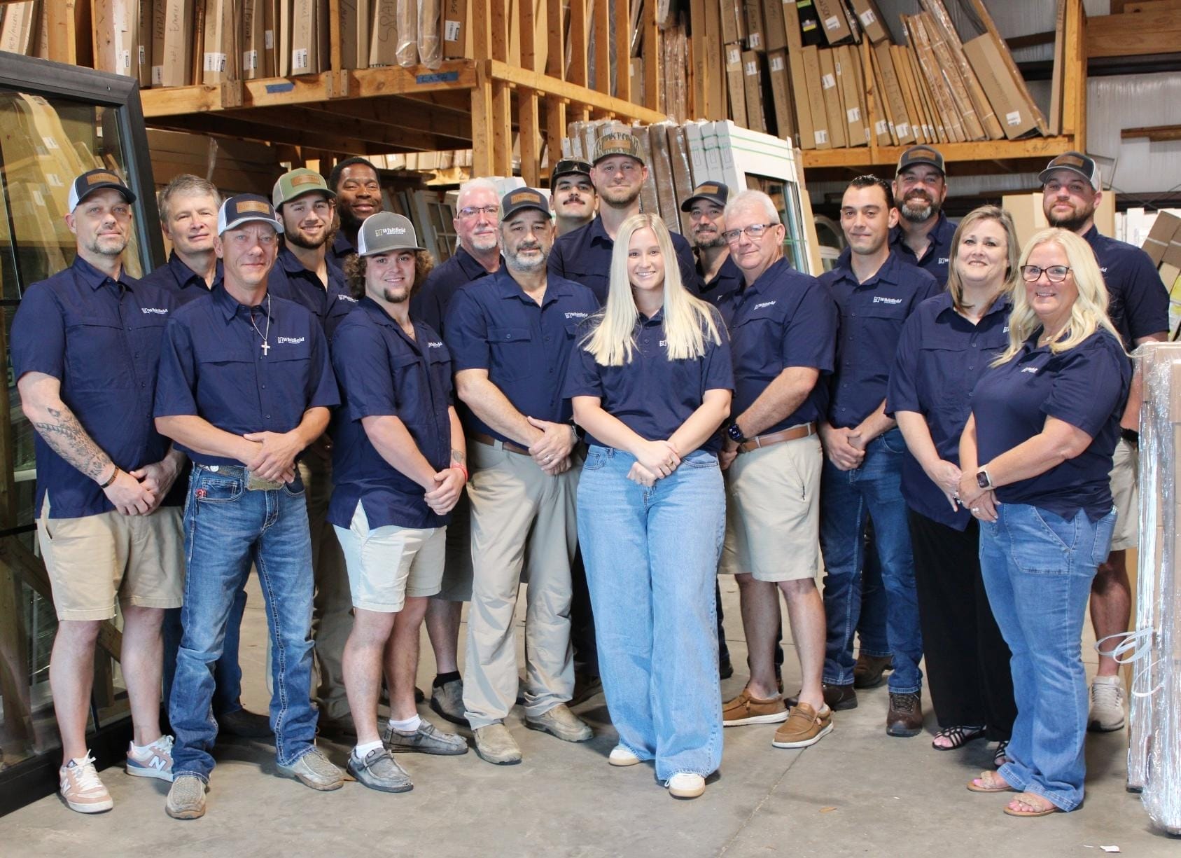 Whitfield employees grouped together for a picture all wearing blue Whitfield Window and Door shirts.