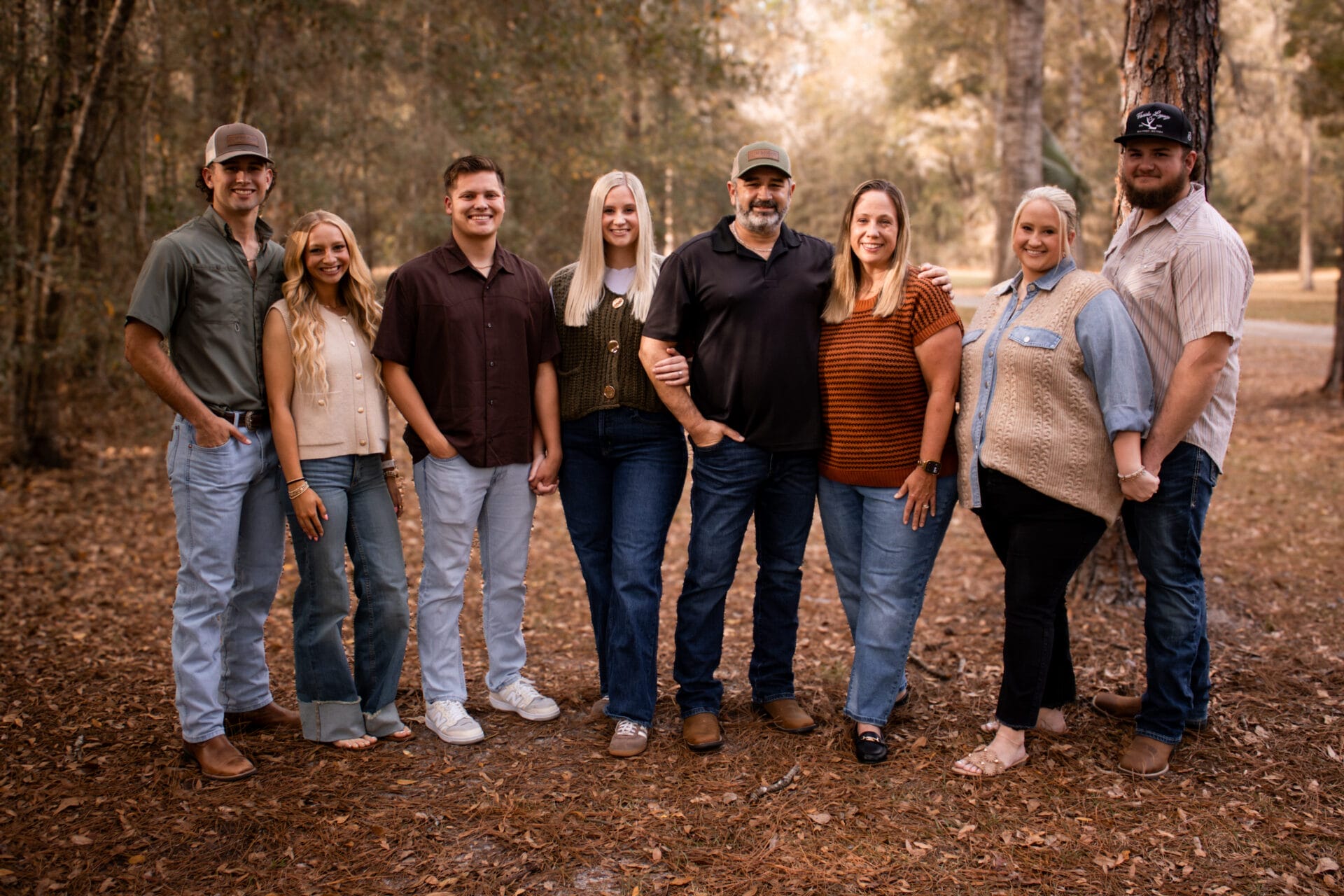 The Whitfield family professional photo underneath a pine tree outdoors.